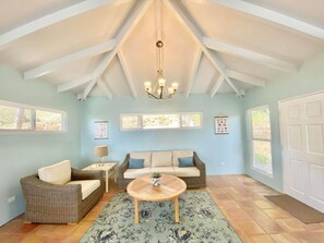 Une pièce spacieuse avec un plafond haut, un lustre, un canapé, une table basse et un tapis.