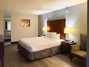 A hotel room with a bed, two bedside lamps, a chair, a nightstand, and a painting on the wall. - Motel6 Mesa, AZ - Downtown (Mesa)