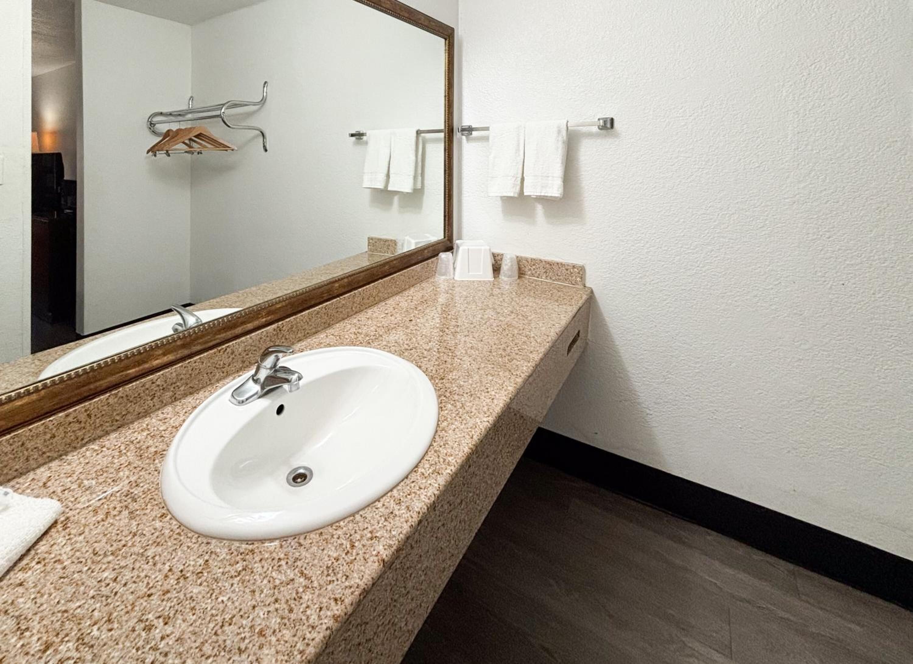 A bathroom with a white sink, a mirror, and a towel rack.