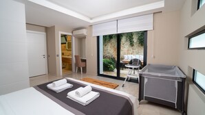 Een moderne hotelkamer met een groot bed, een klein bureau en een balkon met uitzicht op groen.