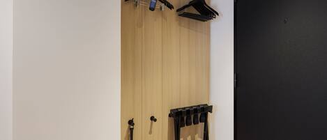 Una habitación con un armario de madera, una puerta negra y un perchero negro con varios ganchos.