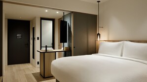 Ein modernes Hotelzimmer mit einem großen Bett, einem Nachttisch, einem Spiegel und einer Wandleuchte.