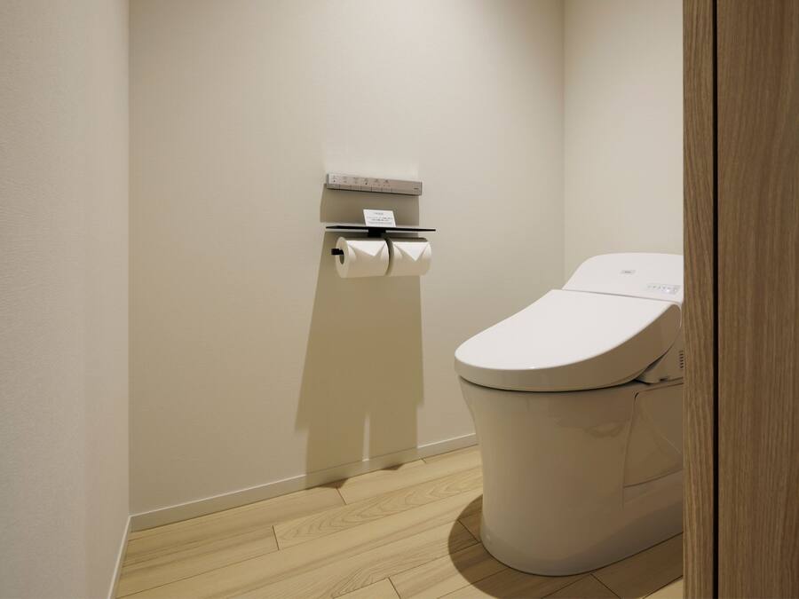 A small, clean bathroom with a toilet, a paper towel dispenser, and a toilet paper roll.