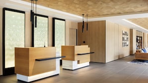 Ein moderner Empfangsbereich mit Holztrespo und einer hohen Decke mit Holzverkleidung, gestaltet im minimalistischen Stil.