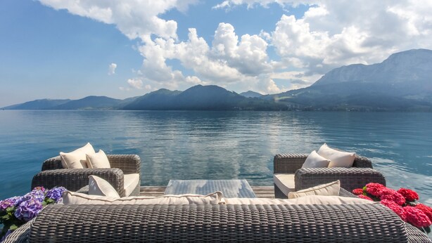 A lakeside view with wicker furniture and flowers. - Hotel Stadler am Attersee (Unterach am Attersee)