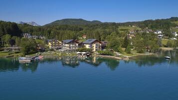 A lakeside hotel with multiple buildings, a dock with boats, and a view of mountains in the background.