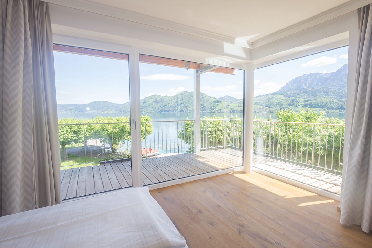 Une chambre dotée d’une grande fenêtre et d’un balcon donnant sur un paysage montagneux.