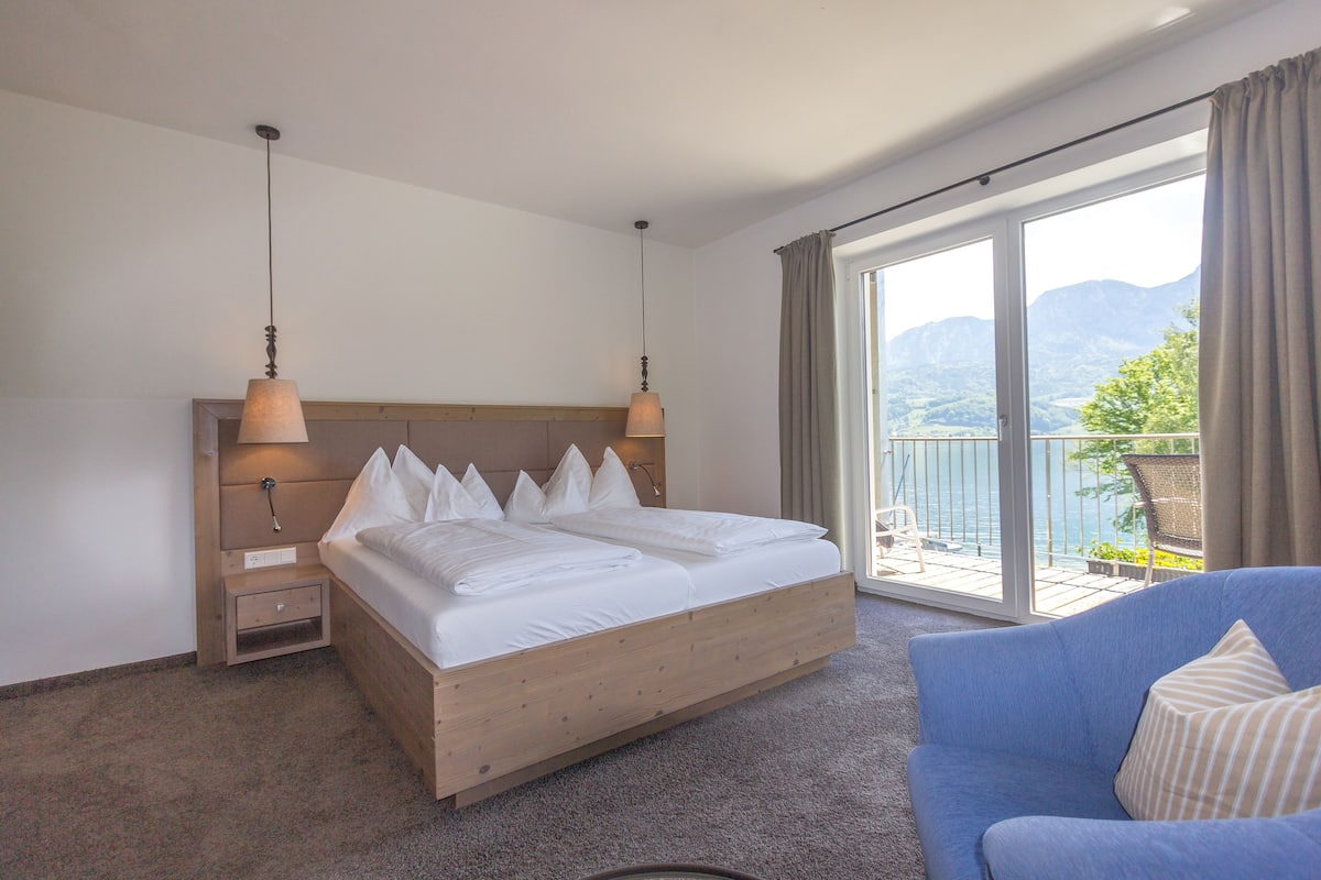 Une chambre à coucher avec un lit en bois, un canapé bleu et un balcon offrant une vue sur les montagnes.