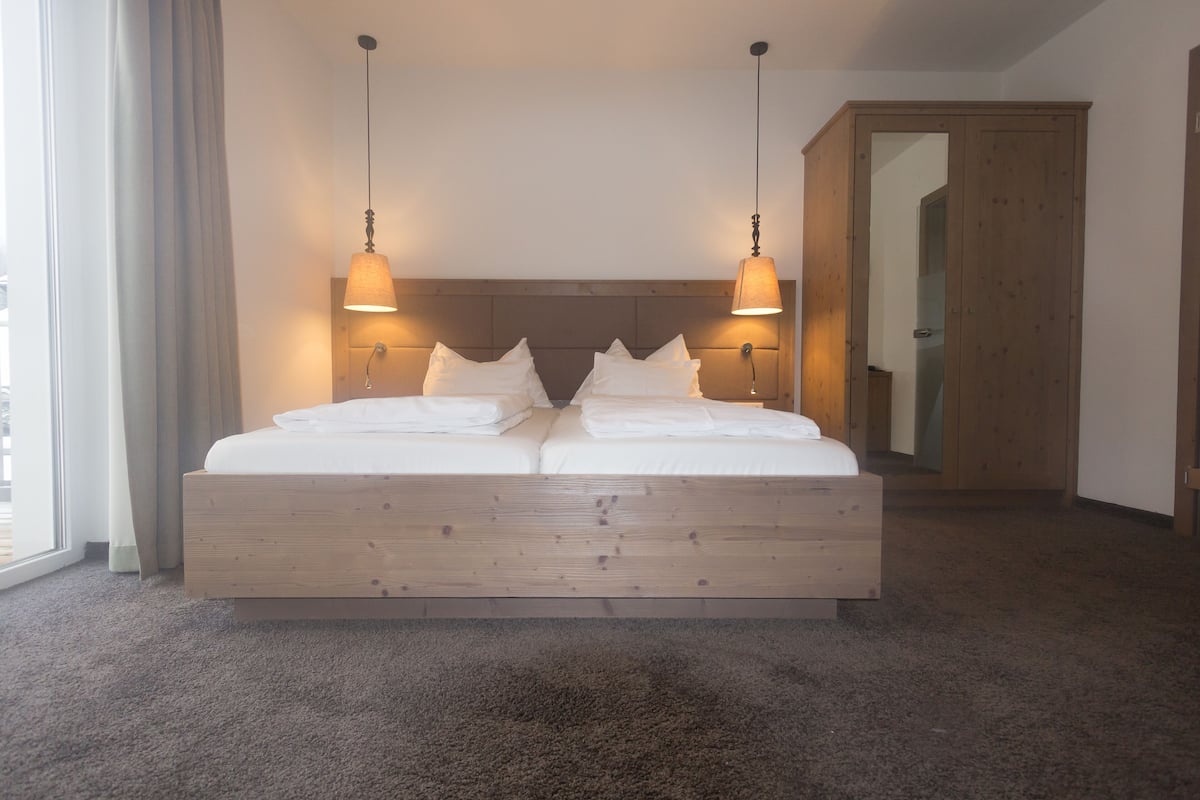 Un grand lit avec une tête de lit en bois, deux lampes de chevet et un miroir au mur.