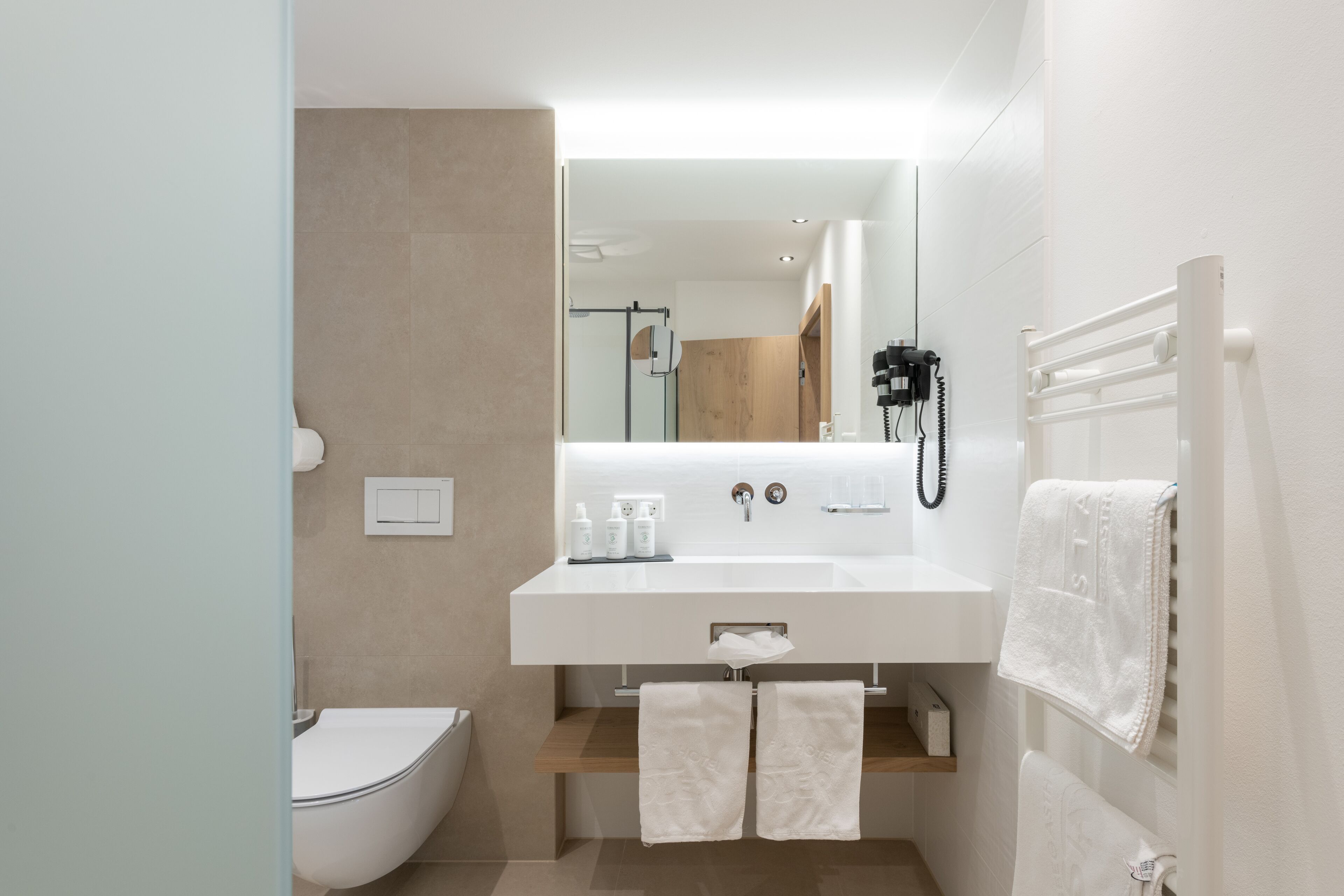 A modern bathroom with a white sink, toilet, and towel rack.