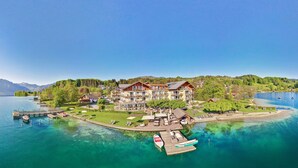 A lakeside hotel with multiple buildings, a dock with boats, and a clear view of the surrounding mountains. - Hotel Stadler am Attersee (Unterach am Attersee)