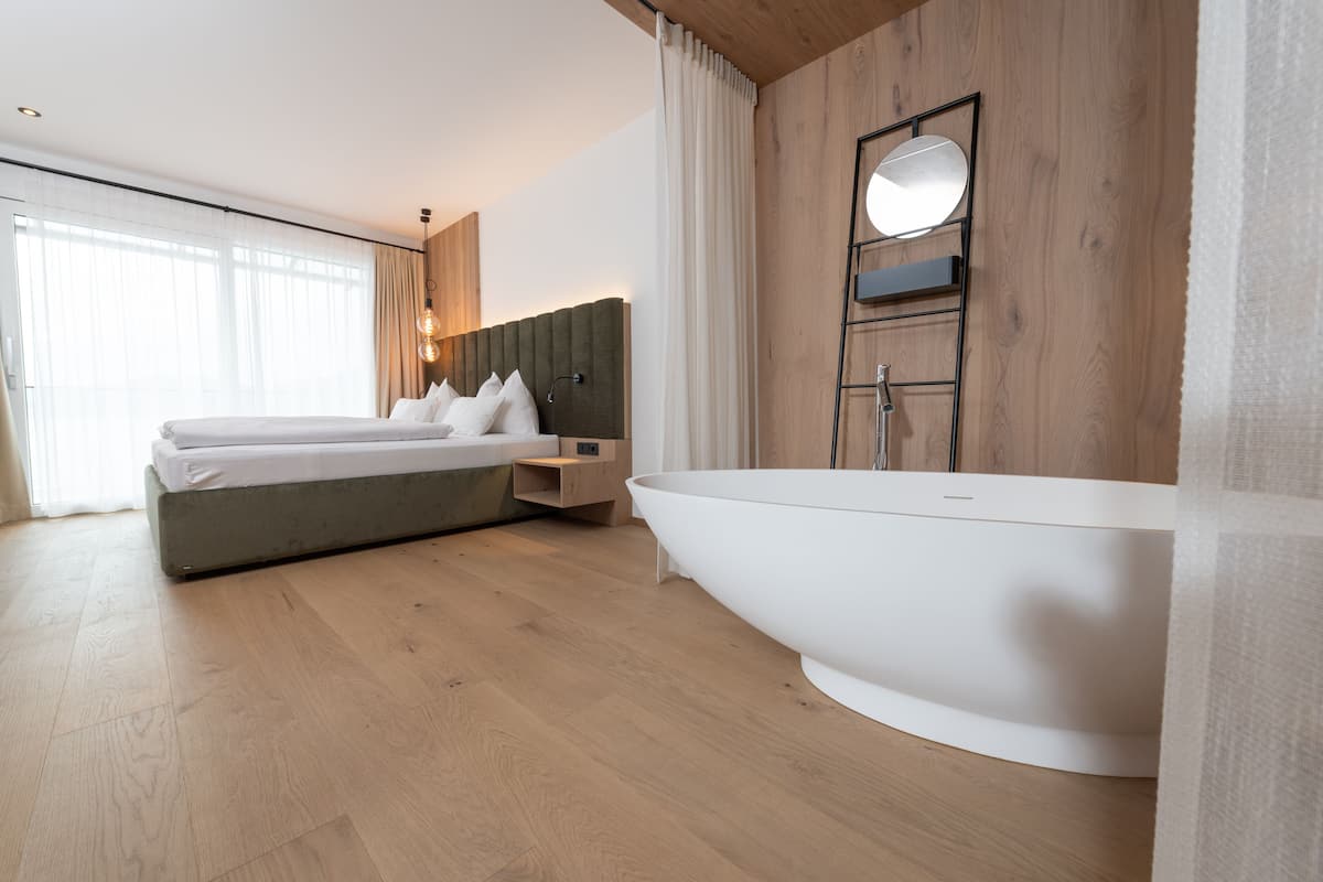 Une chambre d’hôtel moderne avec un grand lit, une baignoire intégr ée et un panneau mural en bois.