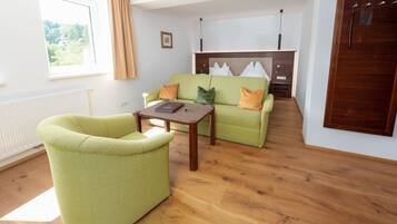 Ein Wohnzimmer mit einem grünen Sofa, einem Holztisch und einem Kamin.