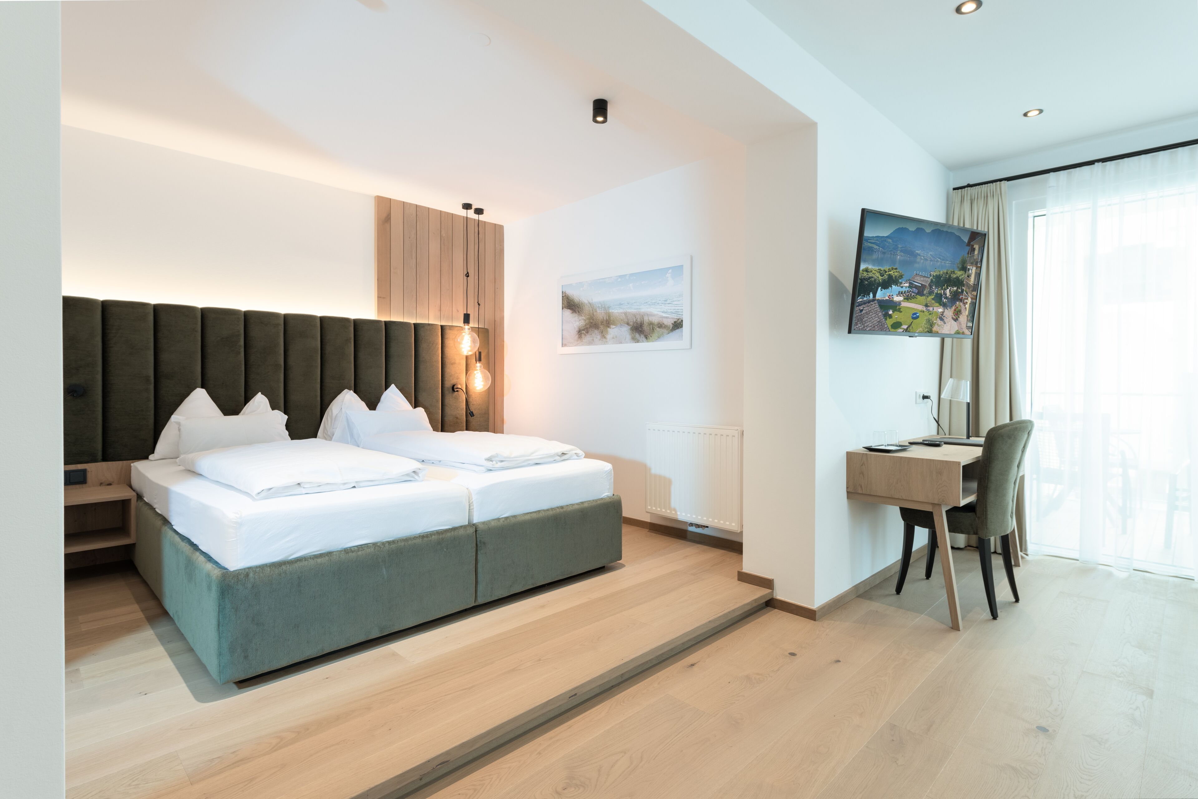 Quarto de hotel moderno com uma cama grande, uma escrivaninha e uma televisão.