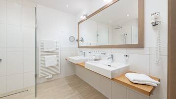 A modern bathroom with two sinks, a large mirror, and a towel rack.