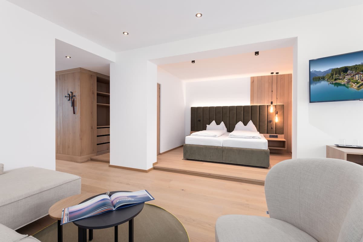 Une chambre d’hôtel moderne dotée d’un grand lit, d’un coin salon avec une table et d’un téléviseur fixé au mur.