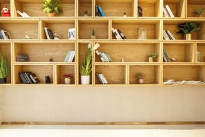 A wooden bookshelf with multiple compartments, some containing books and others with decorative items like plants and figurines. - City Comfort Inn Hotel (Zhongshan Banfu) (Zhongshan)