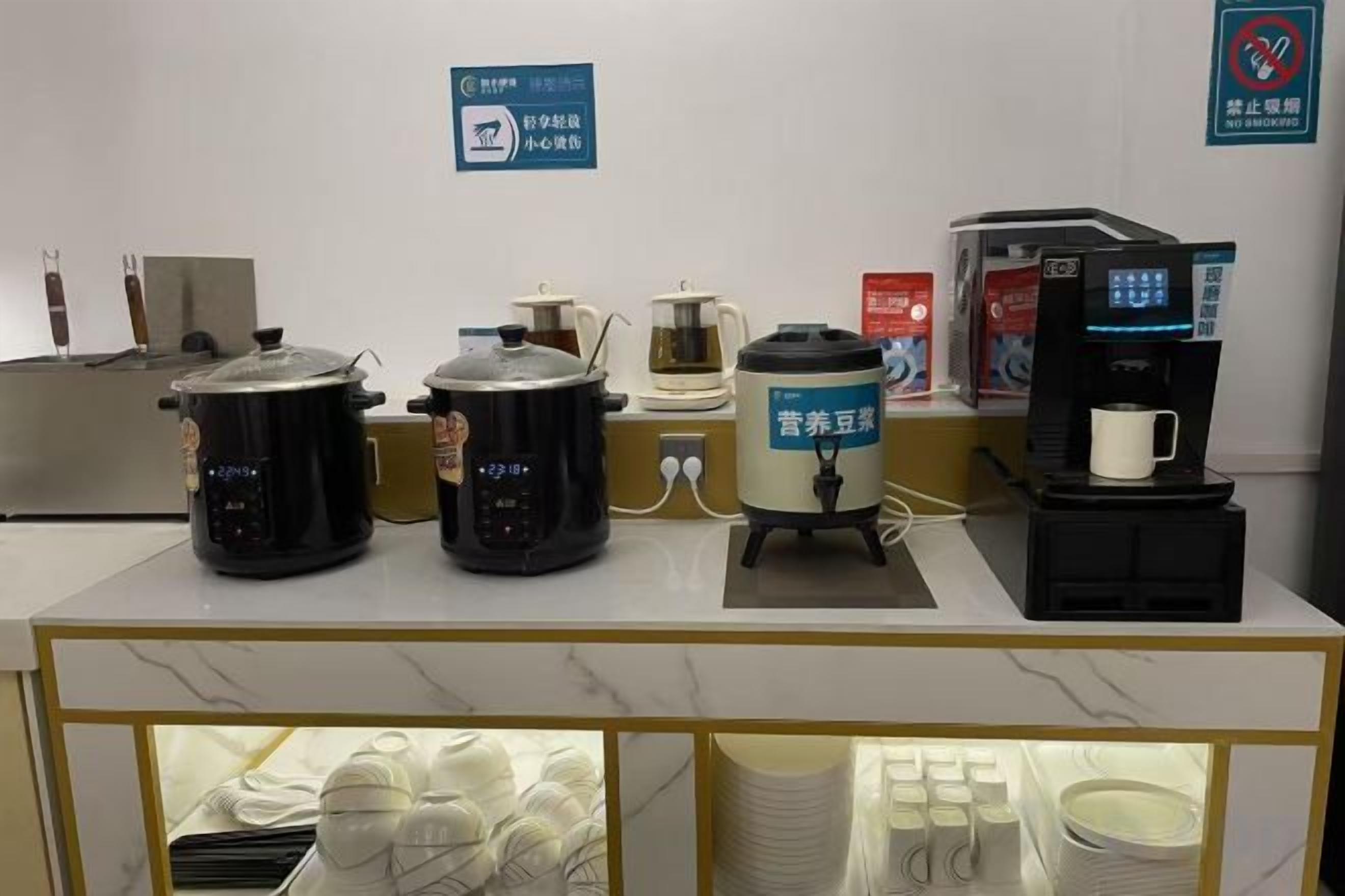 Una zona de cocina con diversos electrodomésticos, incluyendo una cafetera, una cocedora de arroz y una olla de cocción lenta.