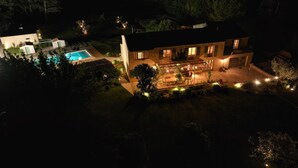 A large house with a swimming pool, a covered patio, and a well-lit garden area at night. - Mas Arietis  (Saint-Rémy-de-Provence)