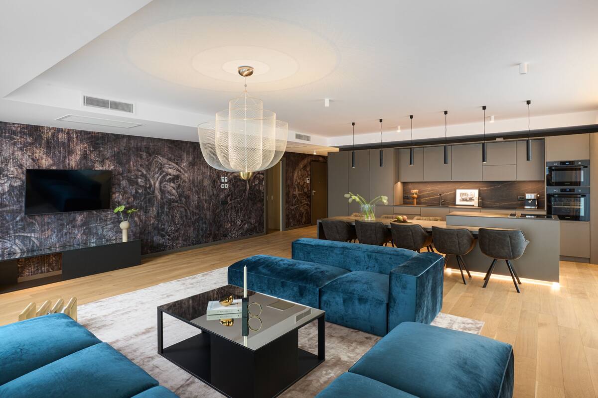 Un salon moderne avec un grand téléviseur, des canapés bleus, une table basse et un coin repas comprenant des chaises et une table.