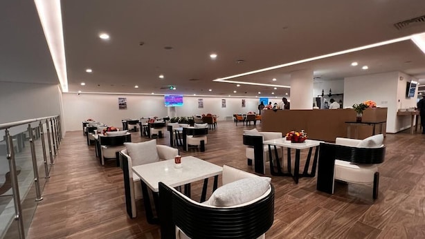Un restaurant moderne doté de plusieurs espaces de restauration, notamment des tables rondes et des banquettes, ainsi qu’un bar.