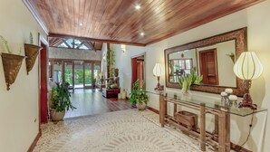 A spacious hallway with a wooden ceiling, a glass console table, and a large mirror. - Beautiful Villa with Pool Gym and Maid (Punta Cana)