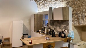 Eine kompakte Küche mit rustikalem Steinmauerwerk, einer Holzinsel mit Barhocker und modernen Geräten.