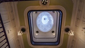 A grand staircase with a central skylight and ornate ceiling details.