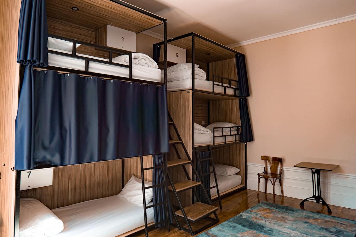A bunk bed room with a wooden ladder, a small table, and a chair.
