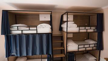 A dormitory-style room with bunk beds, numbered room signs, and a wooden headboard.