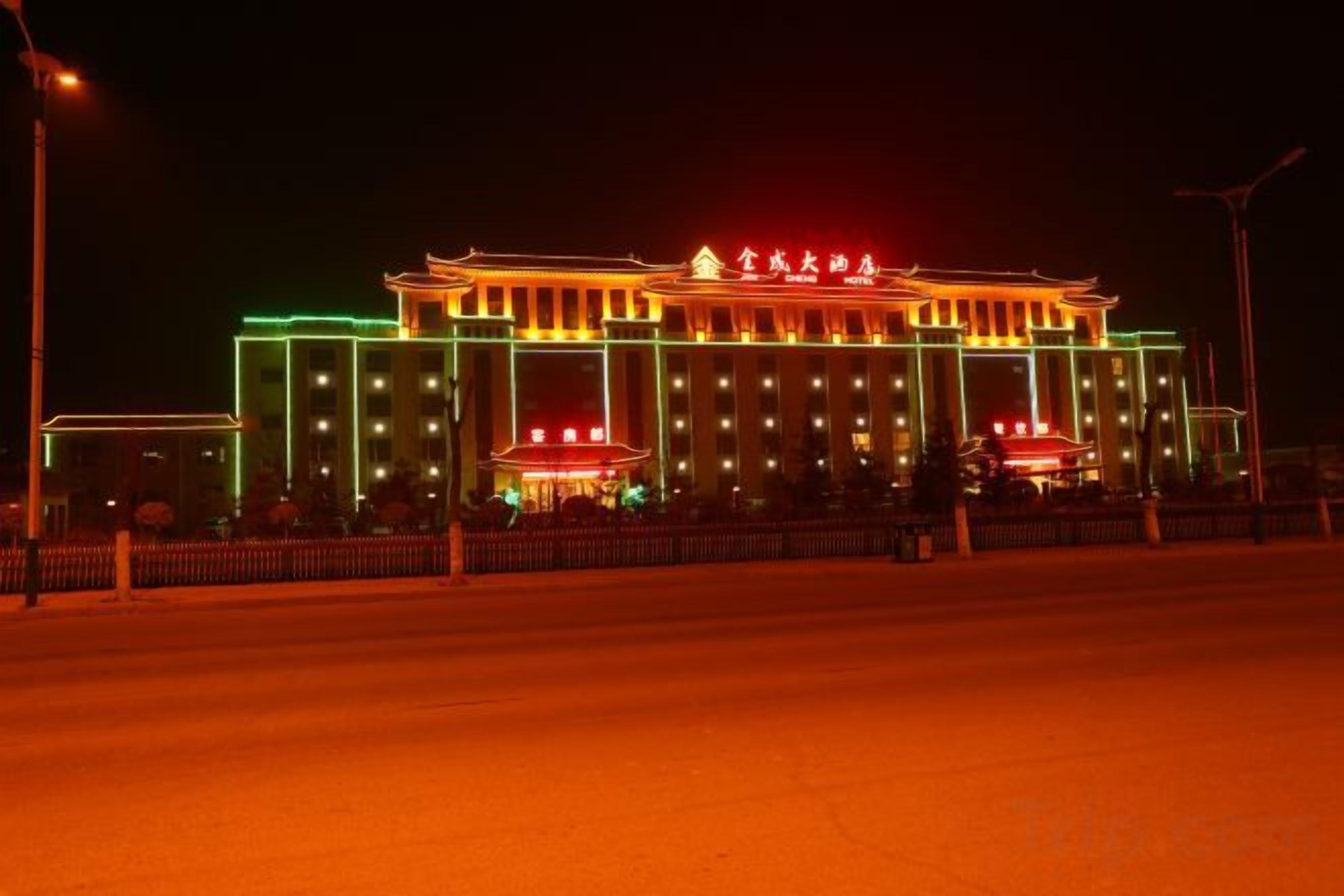 A large, illuminated building with a classical architectural style, featuring a prominent central entrance and multiple windows.