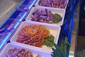 A buffet with various food items in white trays, including sliced vegetables and seafood. - Jin Cheng Hotel (Gangu)