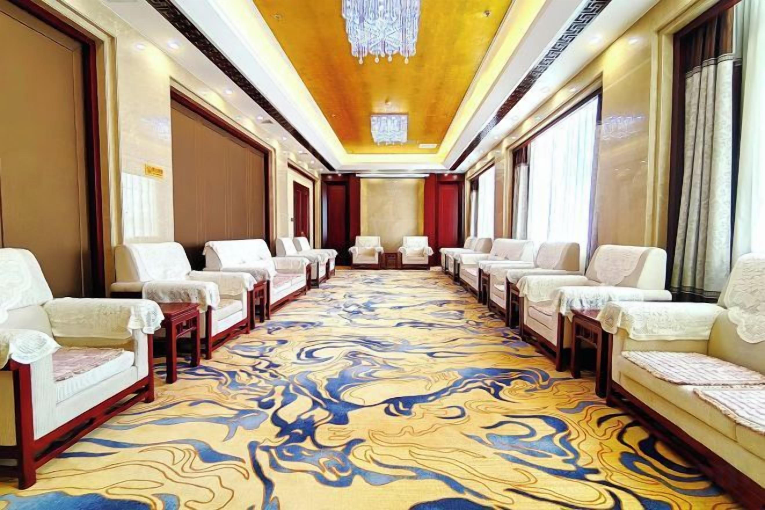 A hotel conference room with rows of chairs, a patterned carpet, and a chandelier.