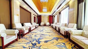 A hotel conference room with rows of chairs, a patterned carpet, and a chandelier.