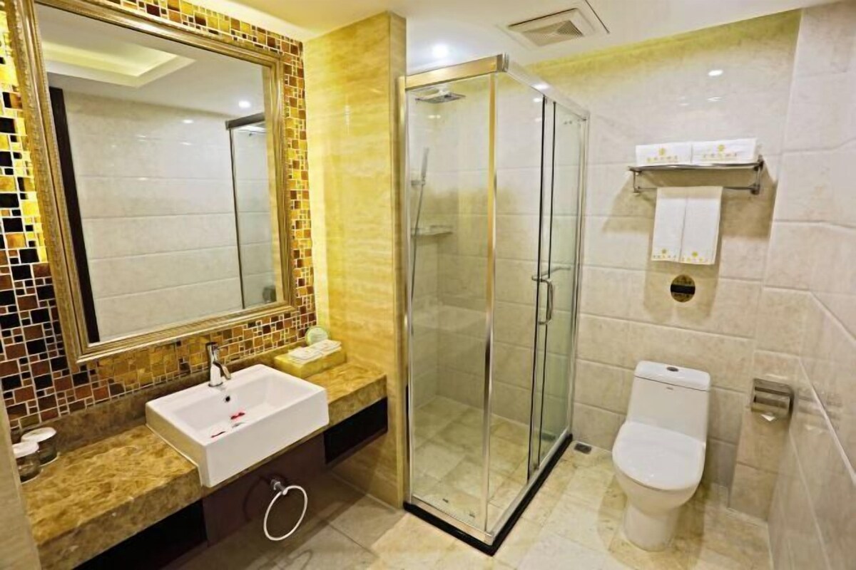A modern bathroom with a glass-enclosed shower, a white sink, and a toilet.