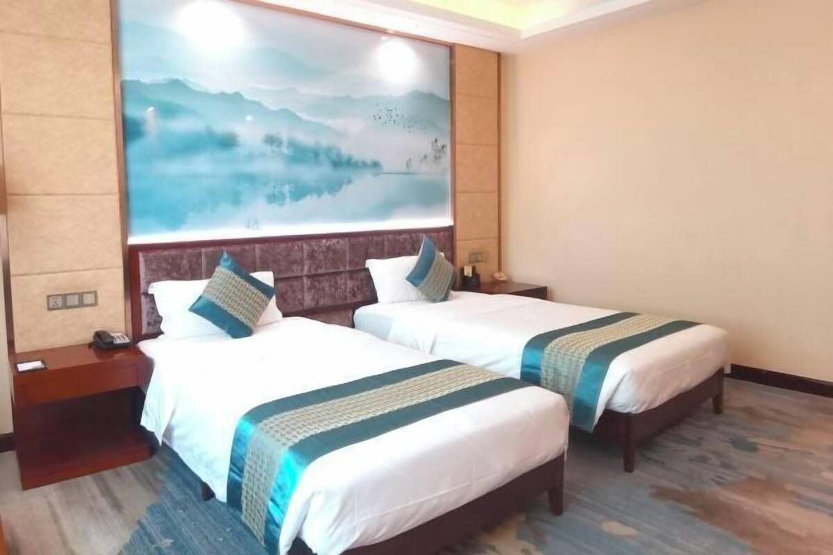 A hotel room with two beds, a large wall mural, and a wooden floor.
