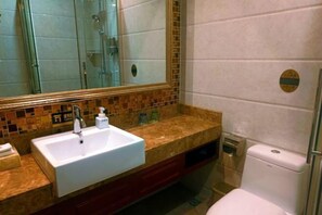 A bathroom with a white sink, a mirror, a shower, and a toilet. - Jin Cheng Hotel (Gangu)