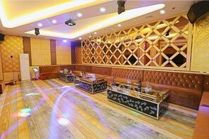 A room with a patterned wall, a stage with a podium, and a seating area with a cushioned bench. - Jin Cheng Hotel (Gangu)
