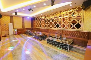 A room with a patterned wall, a stage with a podium, and a seating area with a cushioned bench.
