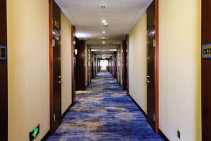 A hotel corridor with a carpeted floor, doors on both sides, and a sign indicating room number 84.