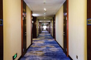 Pasillo de hotel con piso alfombrado, puertas a ambos lados y un cartel que indica la habitación 84.