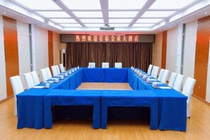 A conference room with a long table, white chairs, and a blue tablecloth. - Jin Cheng Hotel (Gangu)