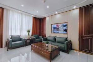 A modern living room with a sofa set, a coffee table, and a television mounted on the wall.