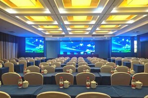 A conference room with rows of tables and chairs, equipped with projectors and screens for presentations. - Jin Cheng Hotel (Gangu)