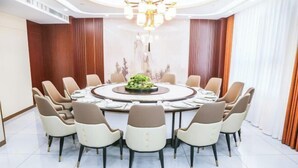 A conference room with a round table, beige and white chairs, and a central floral arrangement. - Jin Cheng Hotel (Gangu)