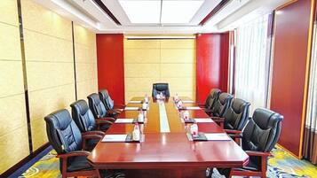 A conference room with a long table, black chairs, and a carpeted floor.