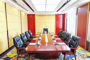 Un salón de conferencias con una larga mesa, sillas negras y piso alfombrado.