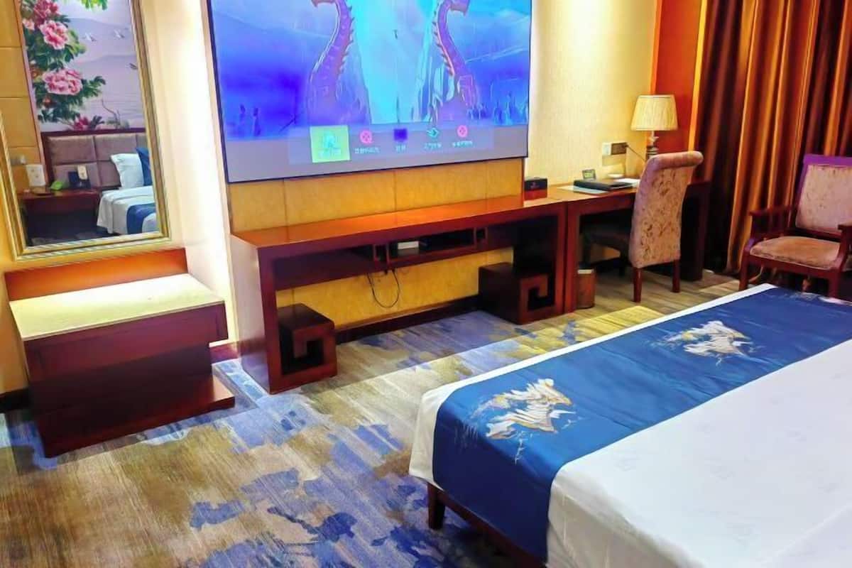A hotel room with a bed, a desk, a television, and a mirror.