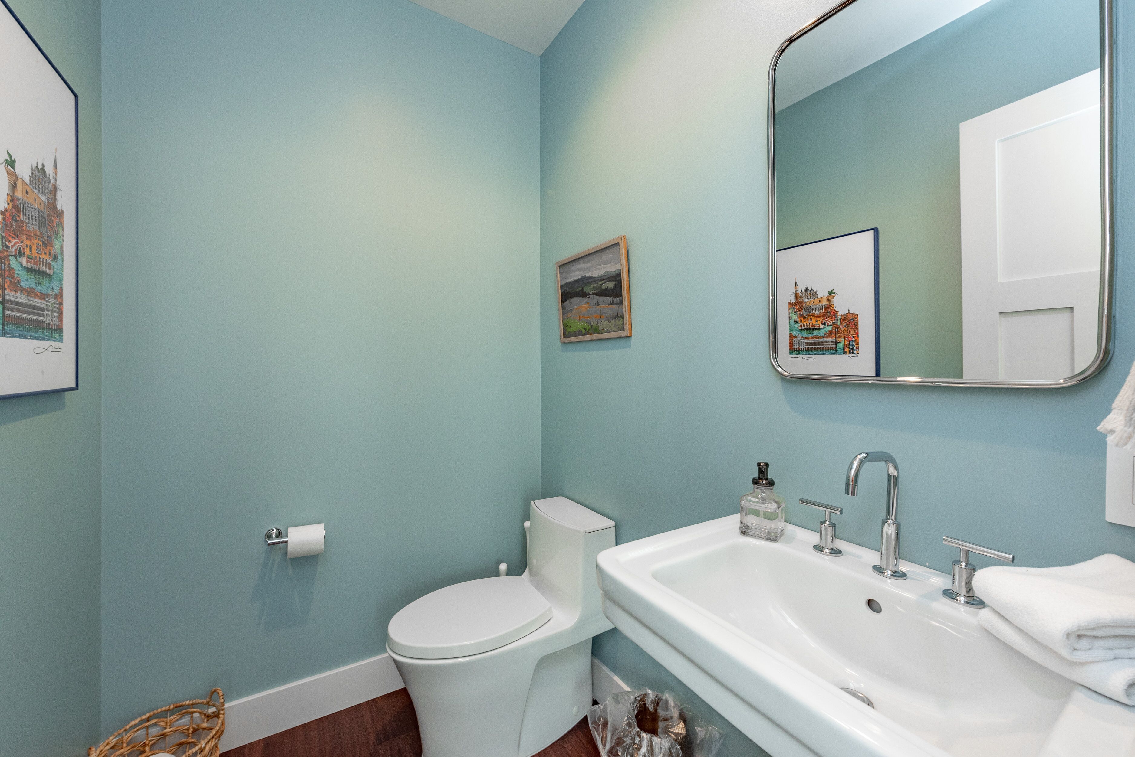 A bathroom with a toilet, sink, and mirror.