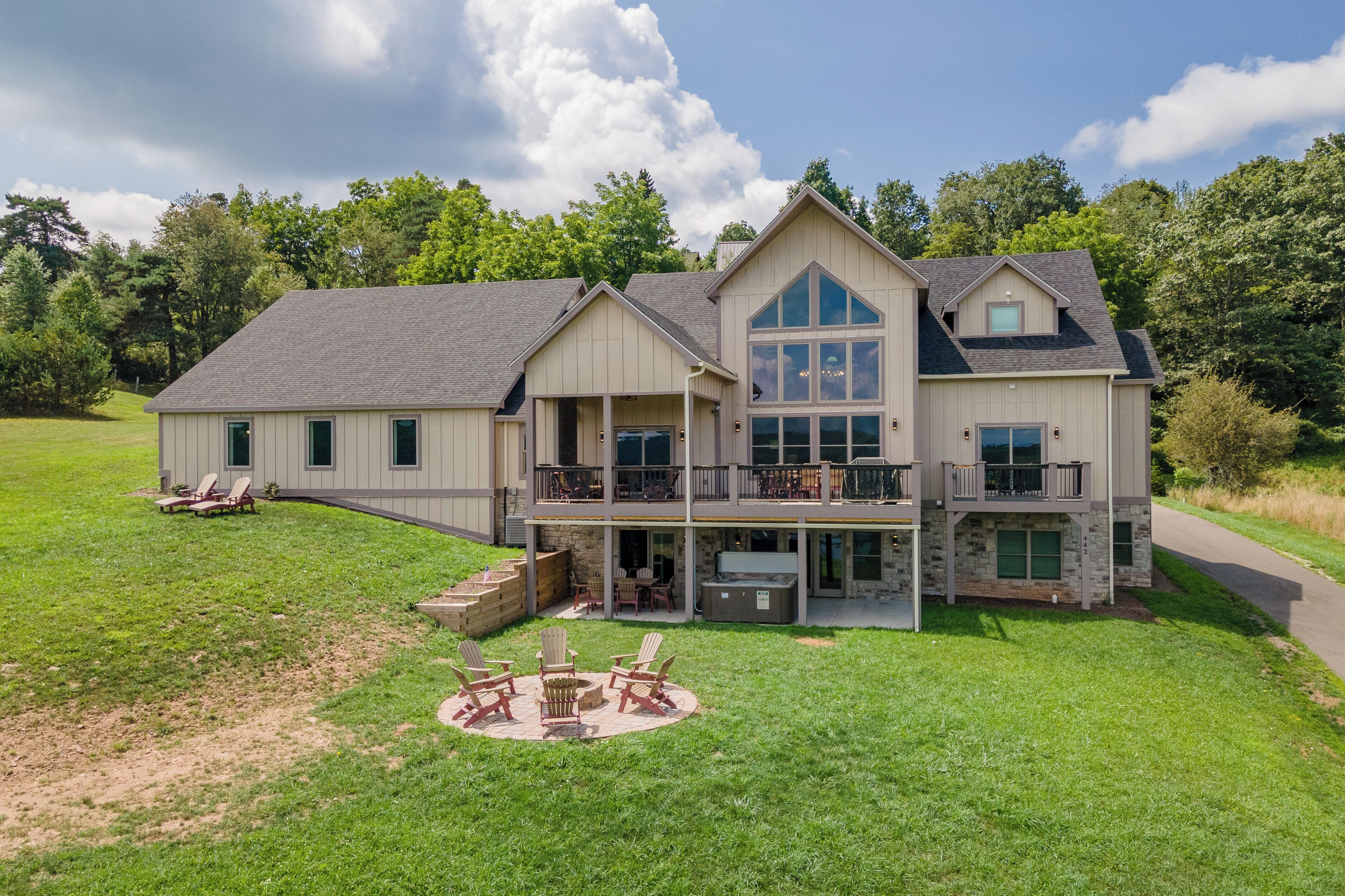 A two-story house with a large front porch, outdoor seating area, and a stone fireplace.